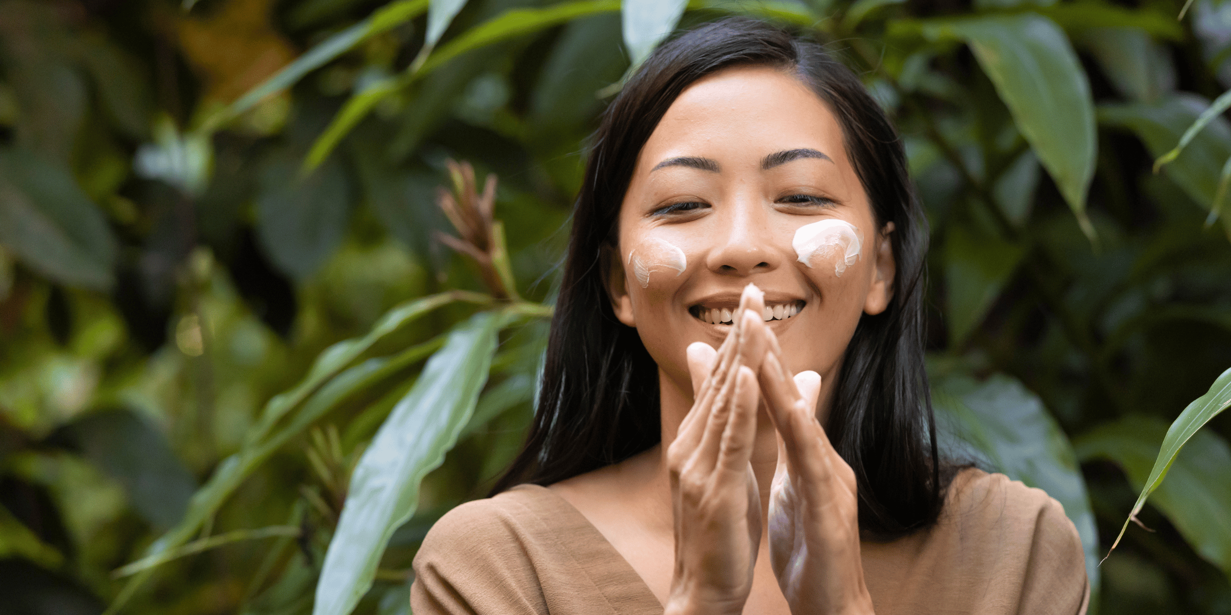 Woman in Hawaiian jungle placing moisturizer on her hands and face