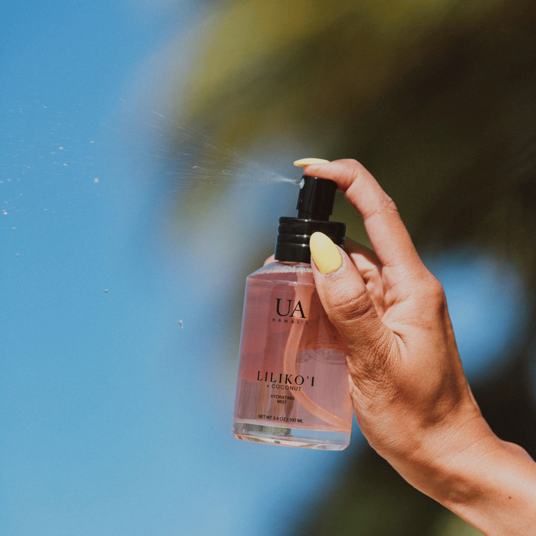 Spritz of Lilikoi Coconut hydrating hair and body mist from hand in hair
